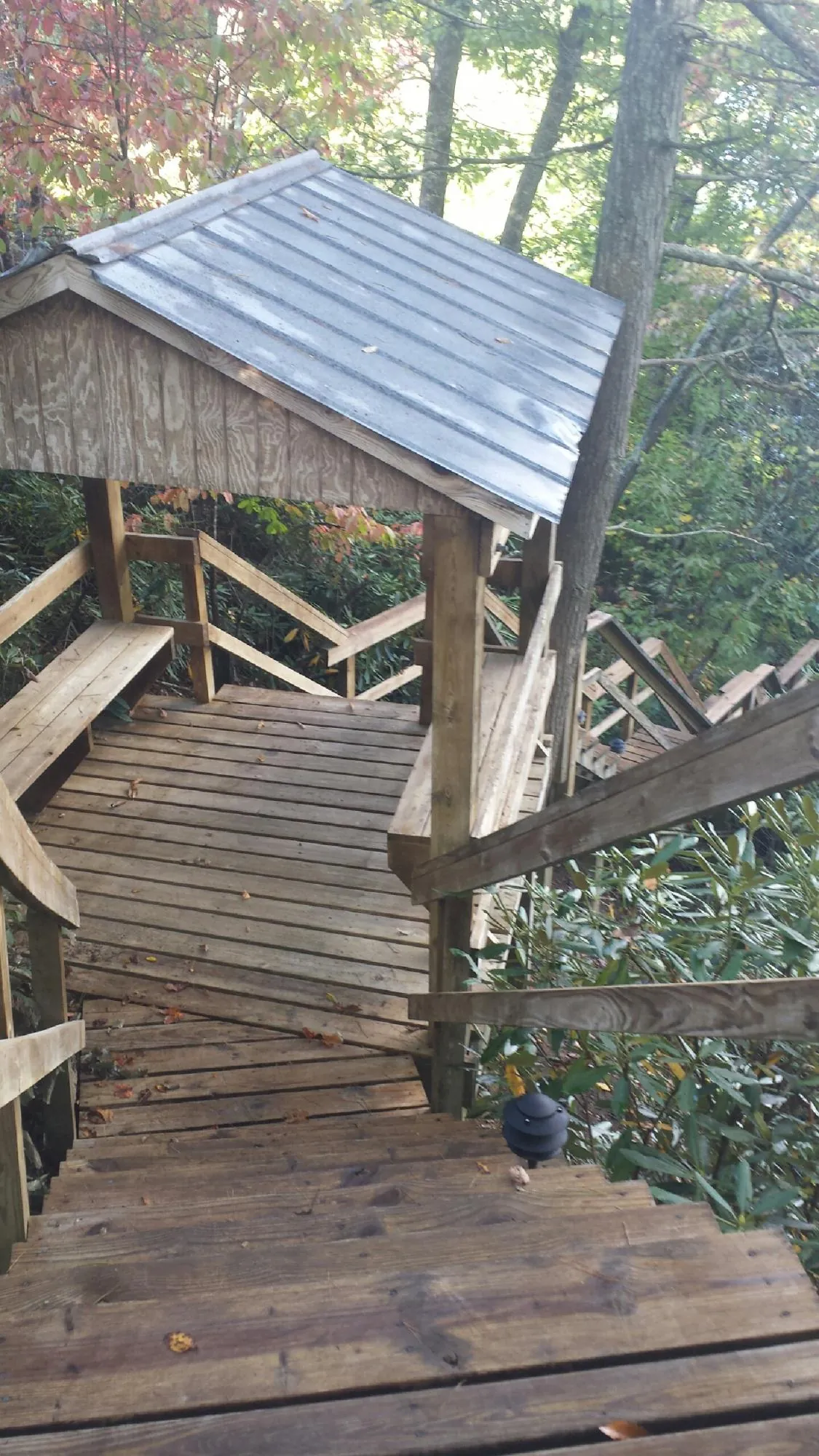 Metal roofed shelter over wooden steps on a wooded walkway — Skylight Repair & Installation work by our crew in Whitehall